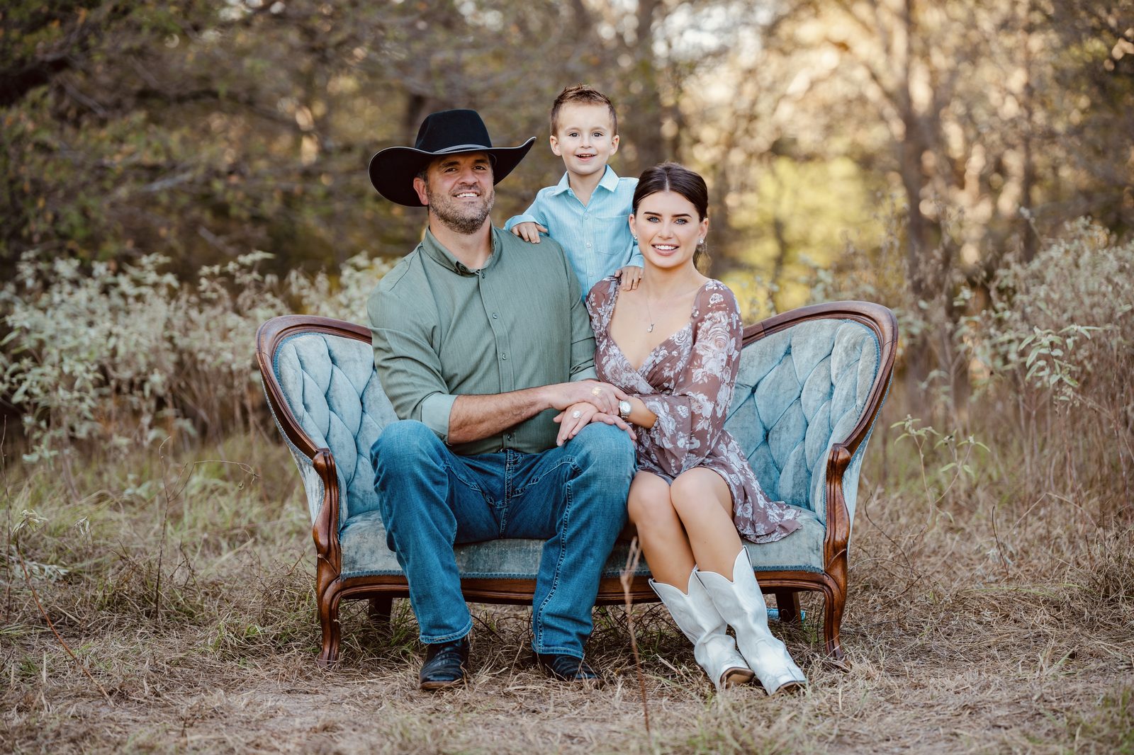 Abigail with her husband and son on a vintage settee in a Texas field